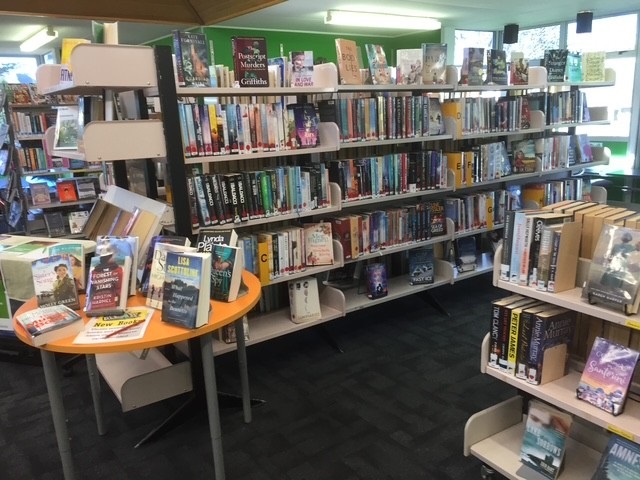 Shelves with books and a small, round yellow table with display books.